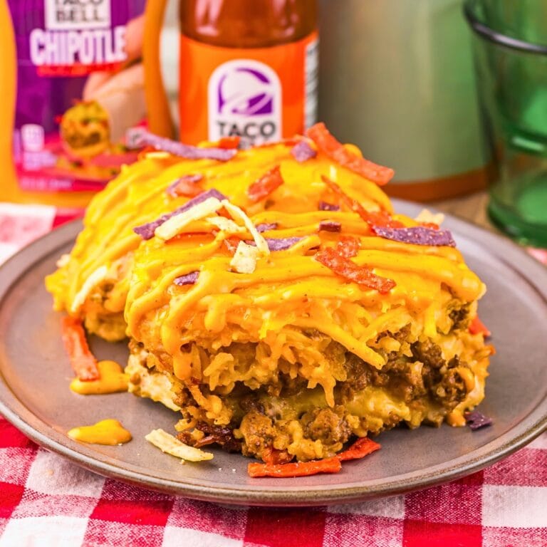 Beef taco casserole with cheese and crispy tortilla strips on a gray plate.
