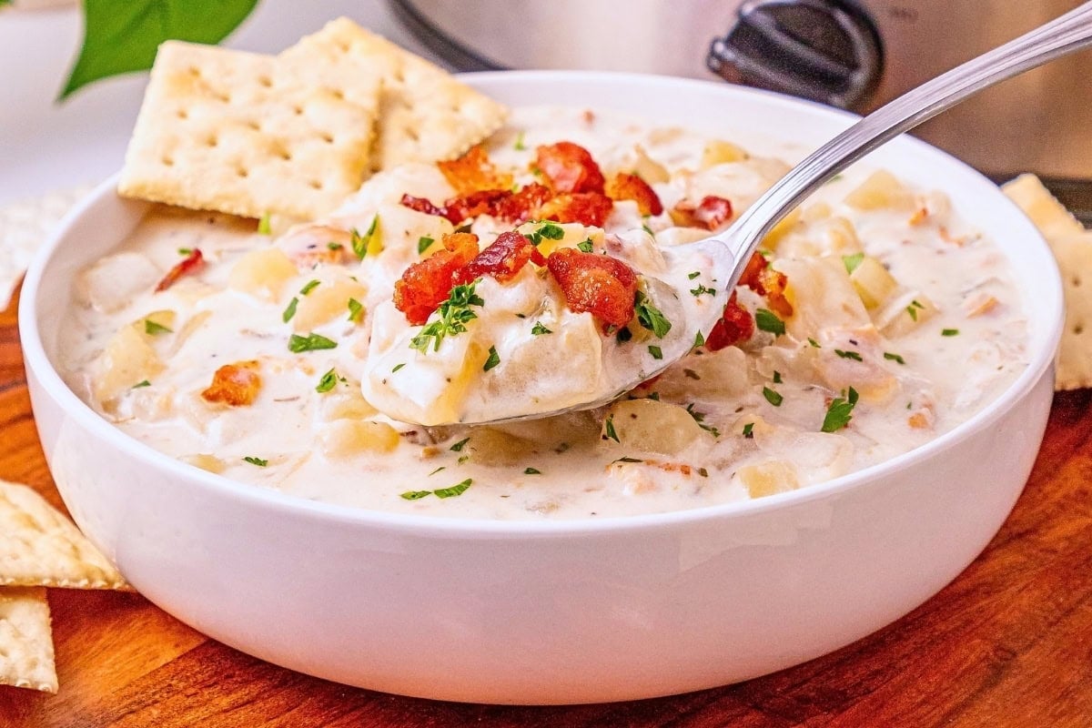 Creamy soup with bacon and herbs in a bowl, served with crackers.