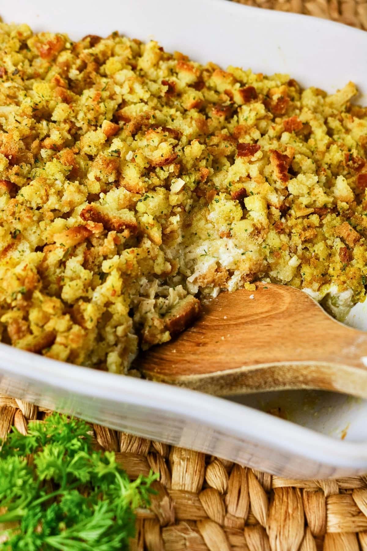Casserole with golden breadcrumb topping and a wooden spoon in a white dish.