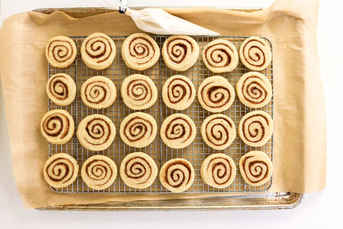 Rows of cinnamon swirl cookies cooling on a wire rack over parchment paper.