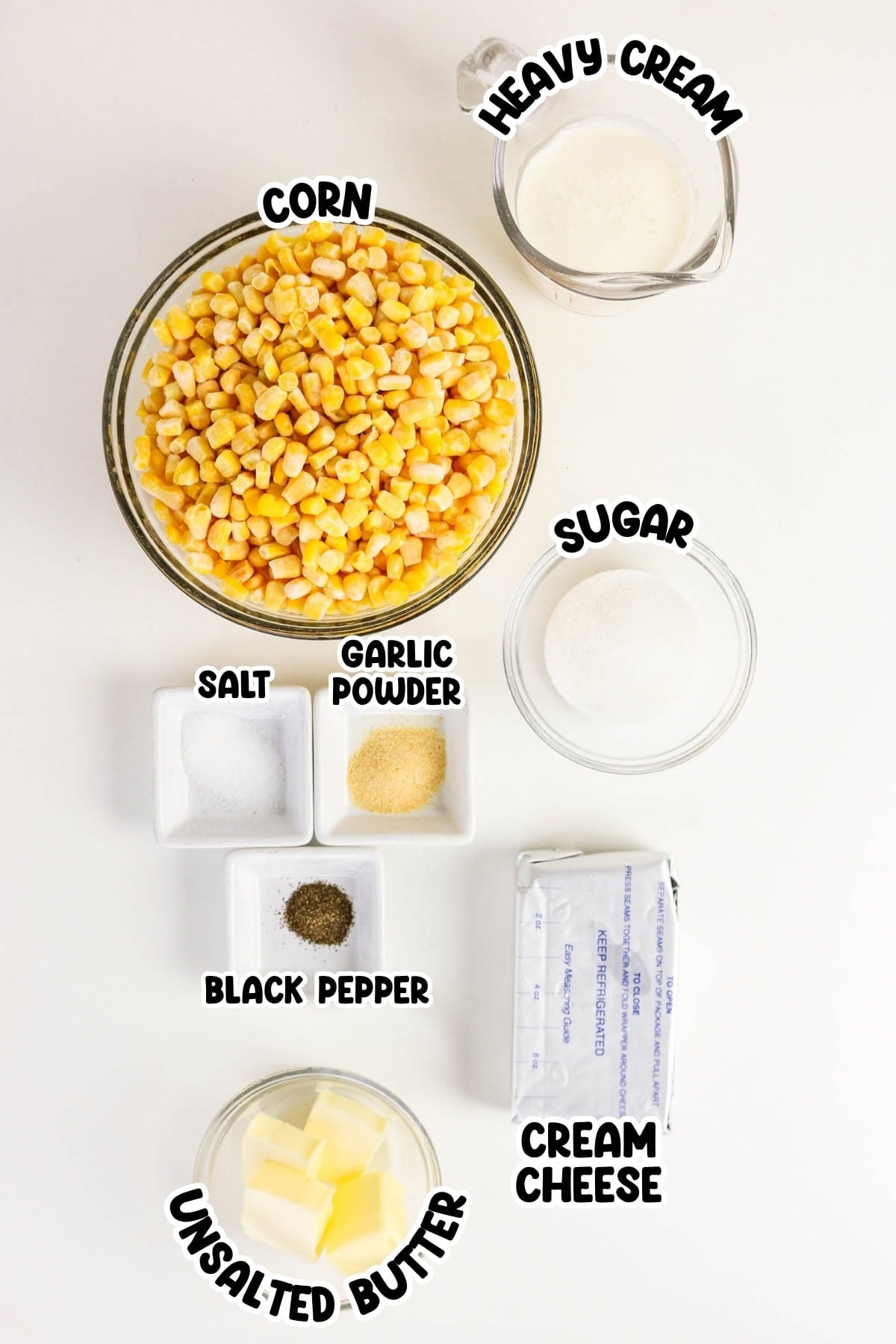 Bowls of corn, heavy cream, sugar, spices, butter, and cream cheese on a table.