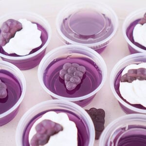 Purple gelatin cups topped with cream and grape-shaped candy.