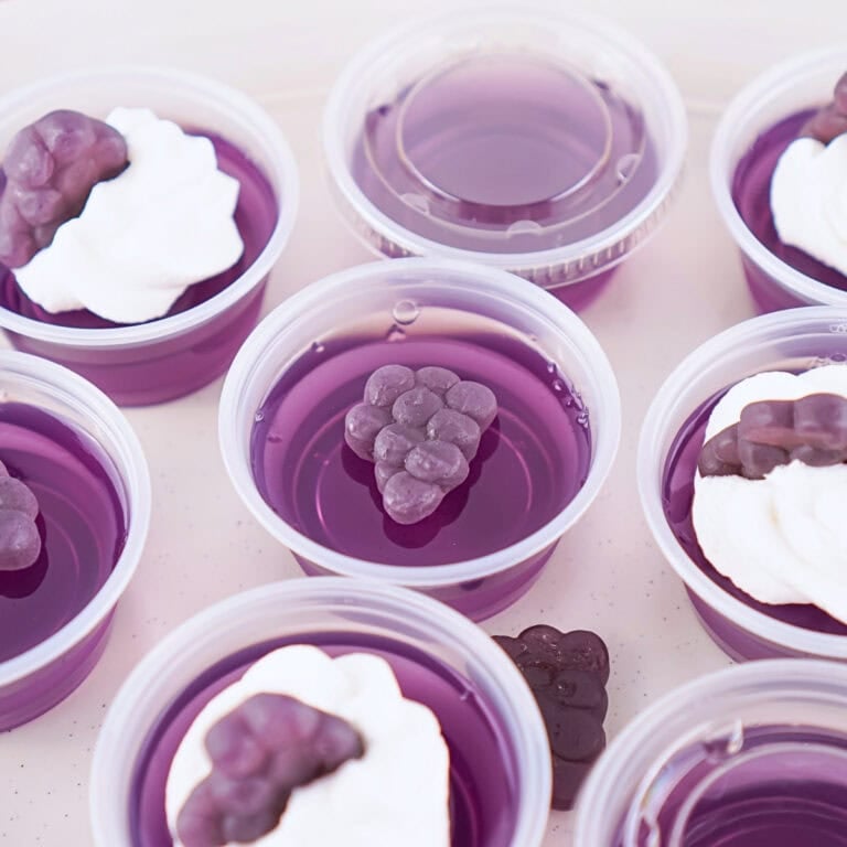 Purple gelatin cups topped with cream and grape-shaped candy.