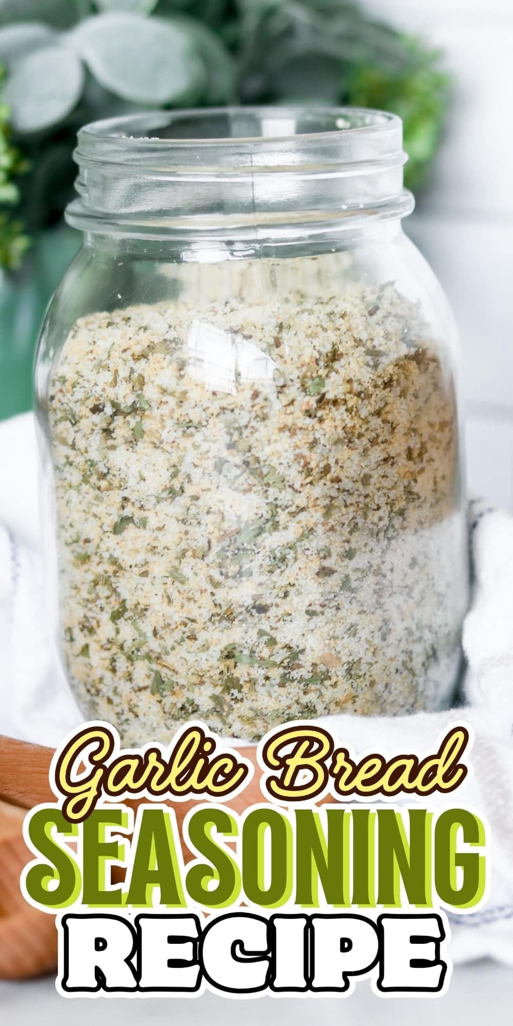 A jar filled with garlic bread seasoning sits on a white cloth.