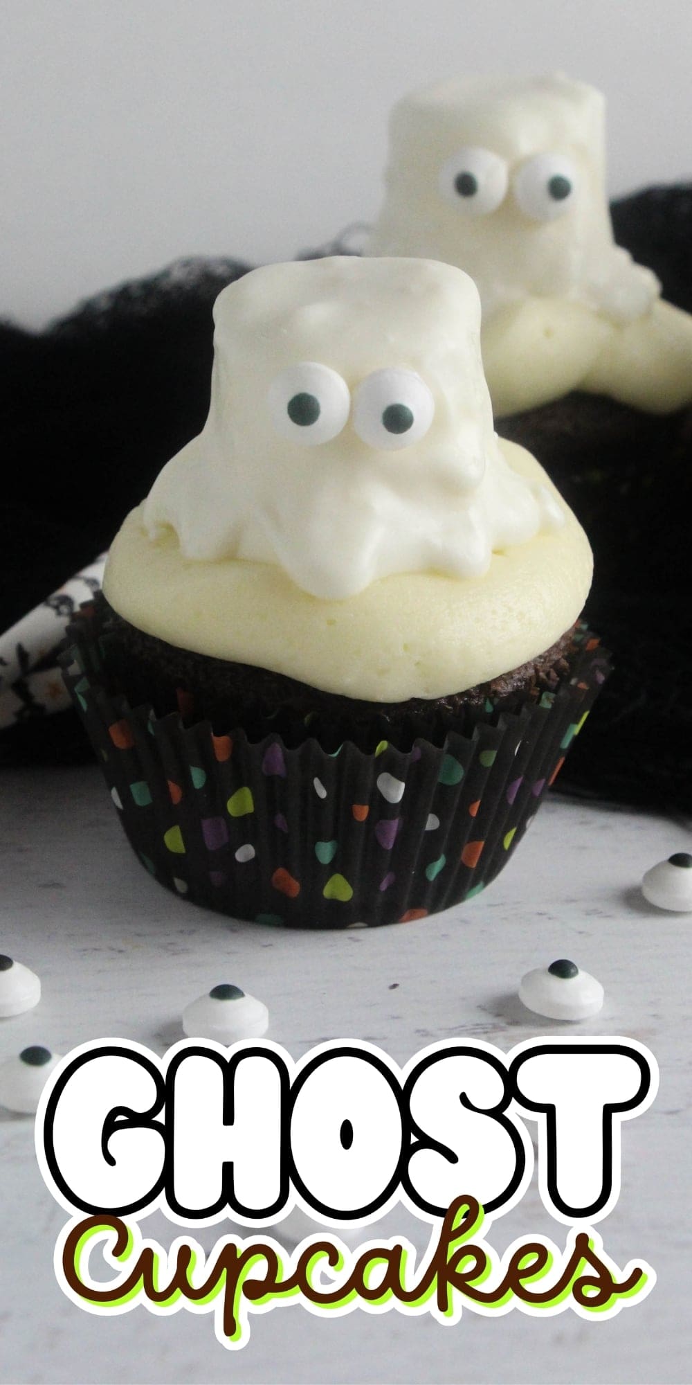 Chocolate cupcake with white ghost-shaped frosting and candy eyes on top.