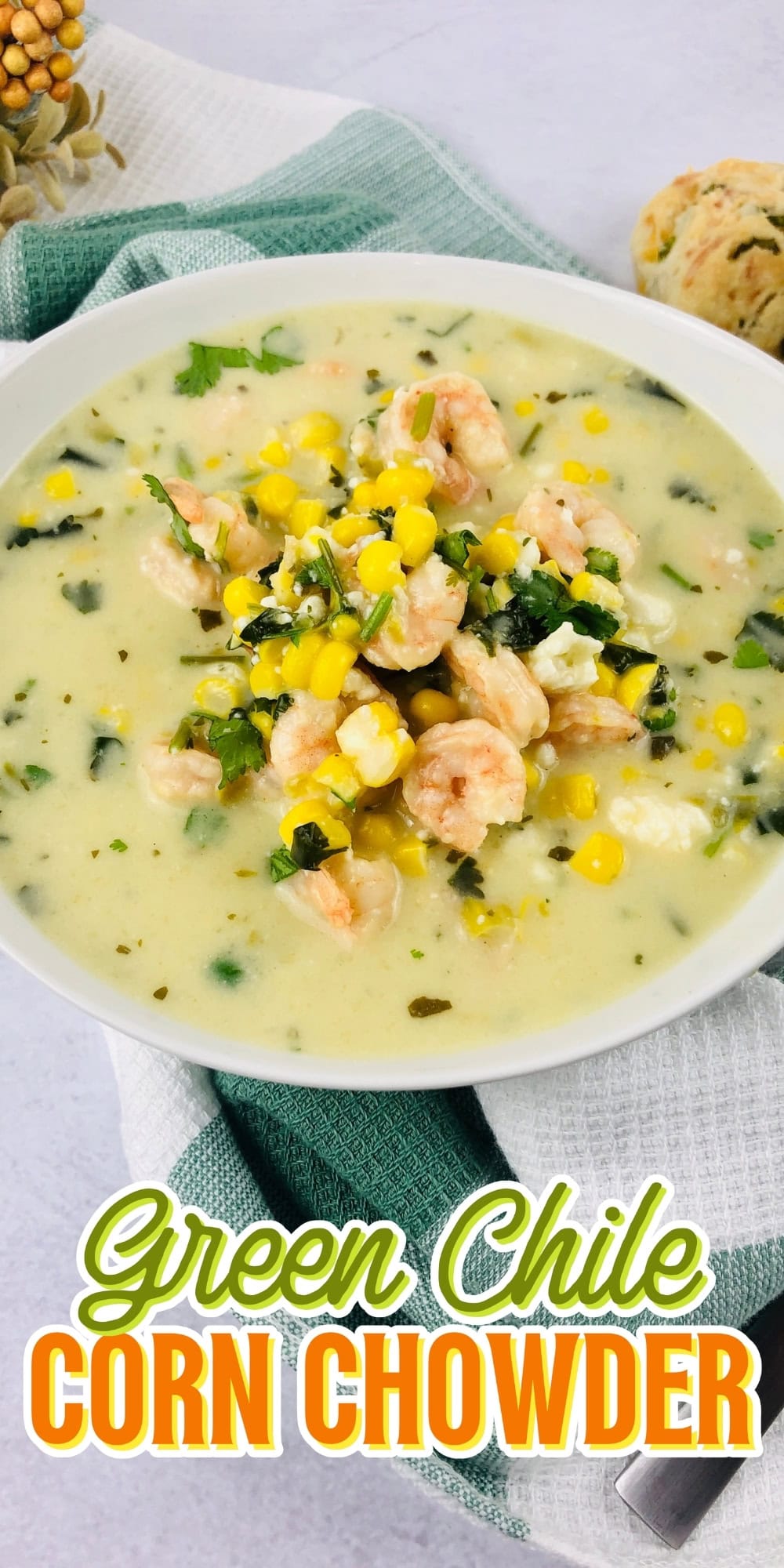 Bowl of green chile corn chowder topped with shrimp, herbs, and corn.