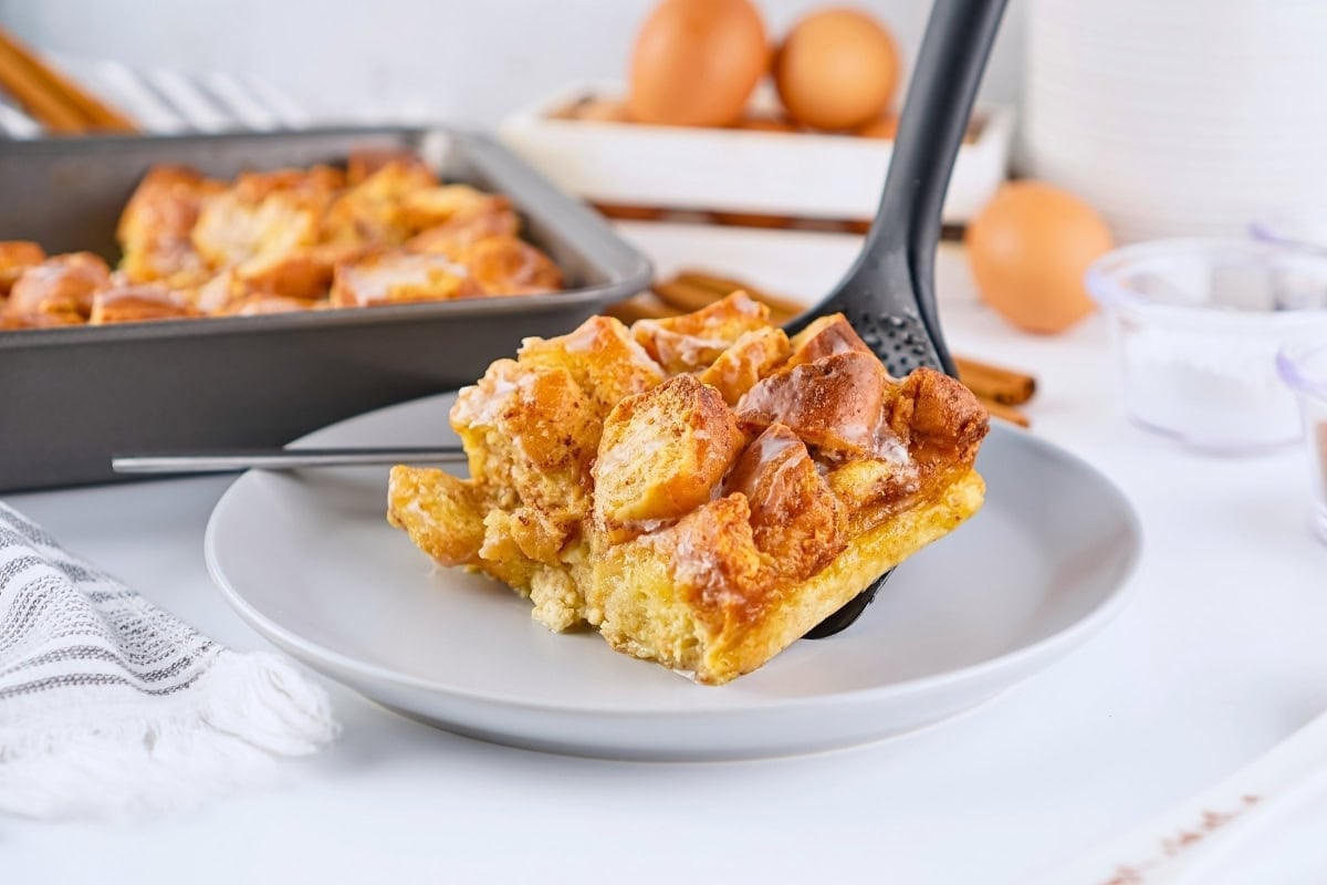 A serving of baked French toast casserole being placed on a plate.