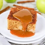 A slice of cake with caramel sauce on top, served on a white plate.