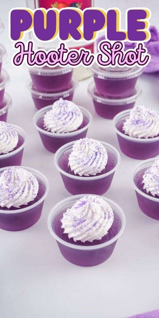 Purple gelatin shots topped with whipped cream and purple sprinkles on a table.