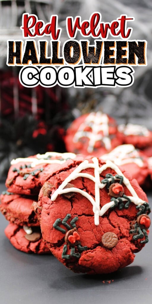 Red velvet cookies decorated with webs and leaves, stacked on a dark surface.