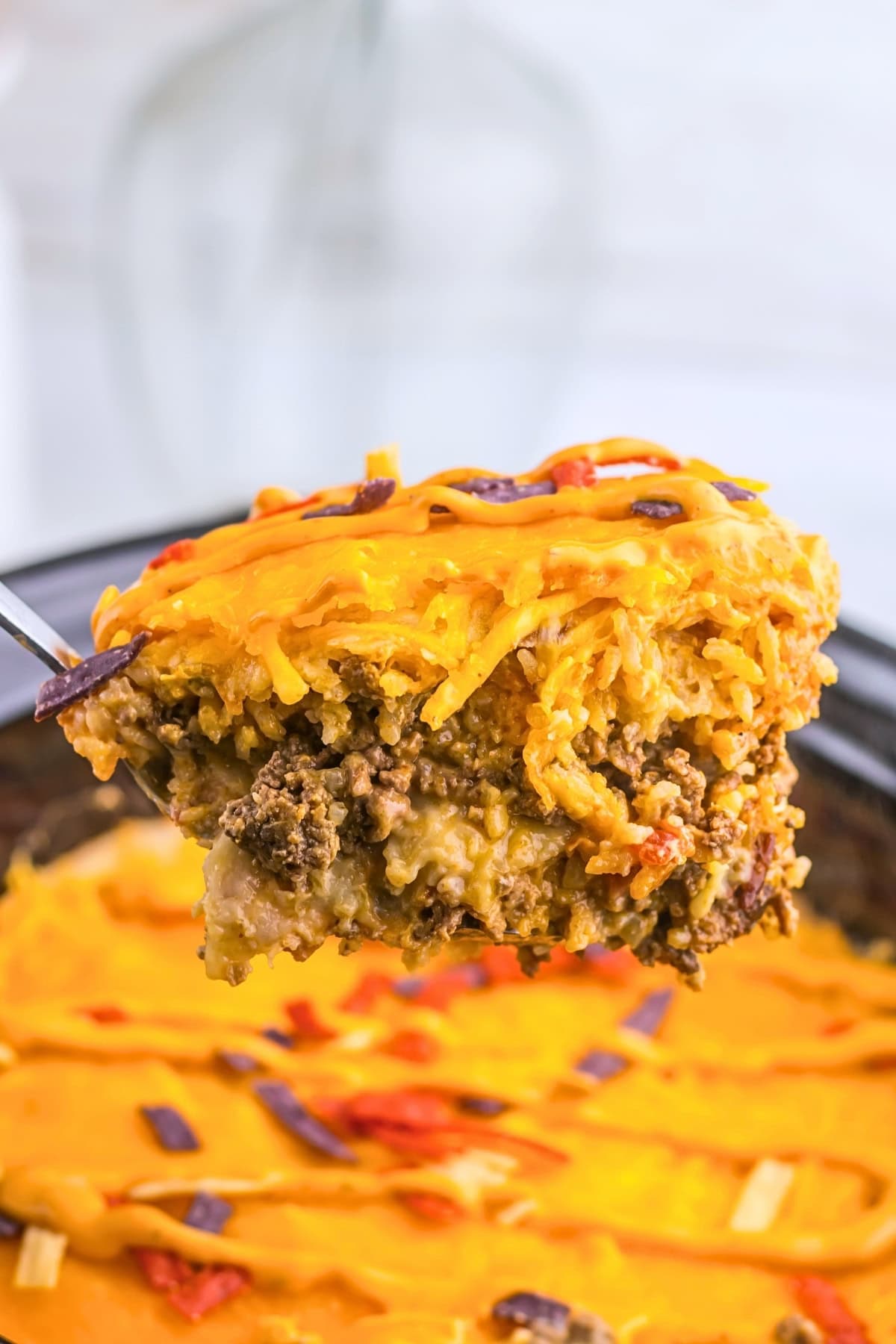 Cheesy casserole with ground beef, shredded cheese, and tortilla strips on top.