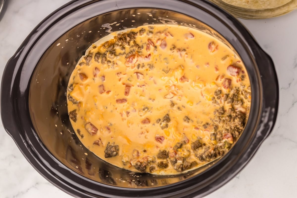 Cheese dip with ground beef and tomatoes in a slow cooker.