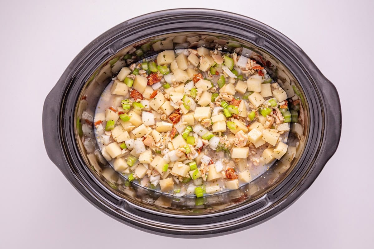 Diced potatoes, celery, and bacon in a slow cooker with broth.
