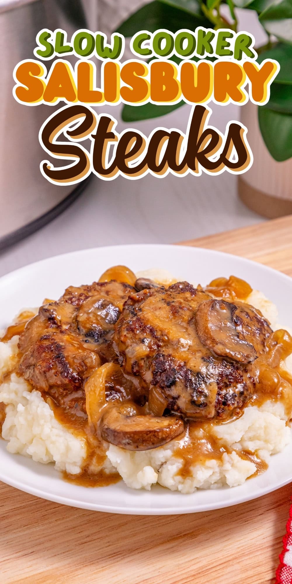 Two Salisbury steaks with gravy and onions over mashed potatoes on a plate.