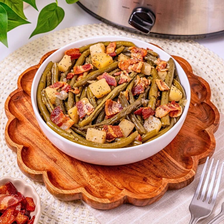 Bowl of green beans, potatoes, and bacon on a wooden tray.
