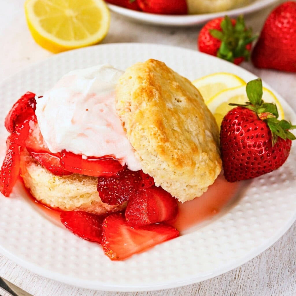 Strawberry shortcake with whipped cream, fresh strawberries, and a lemon slice.