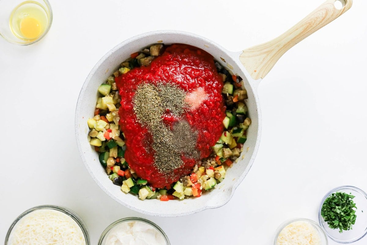 Add tomatoes, salt, pepper, and herbs to sautéed veggies in a pan; stir to mix.