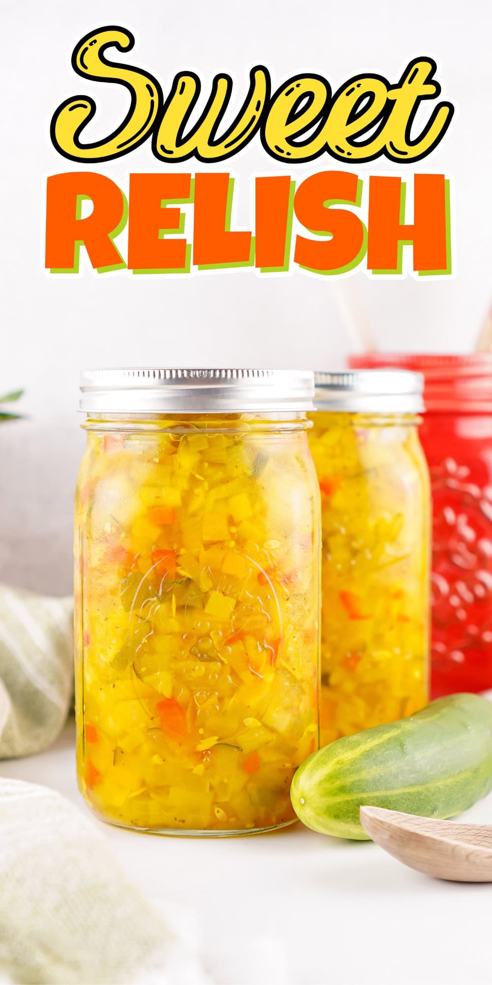 Jar of sweet relish with cucumber and red jar in the background.