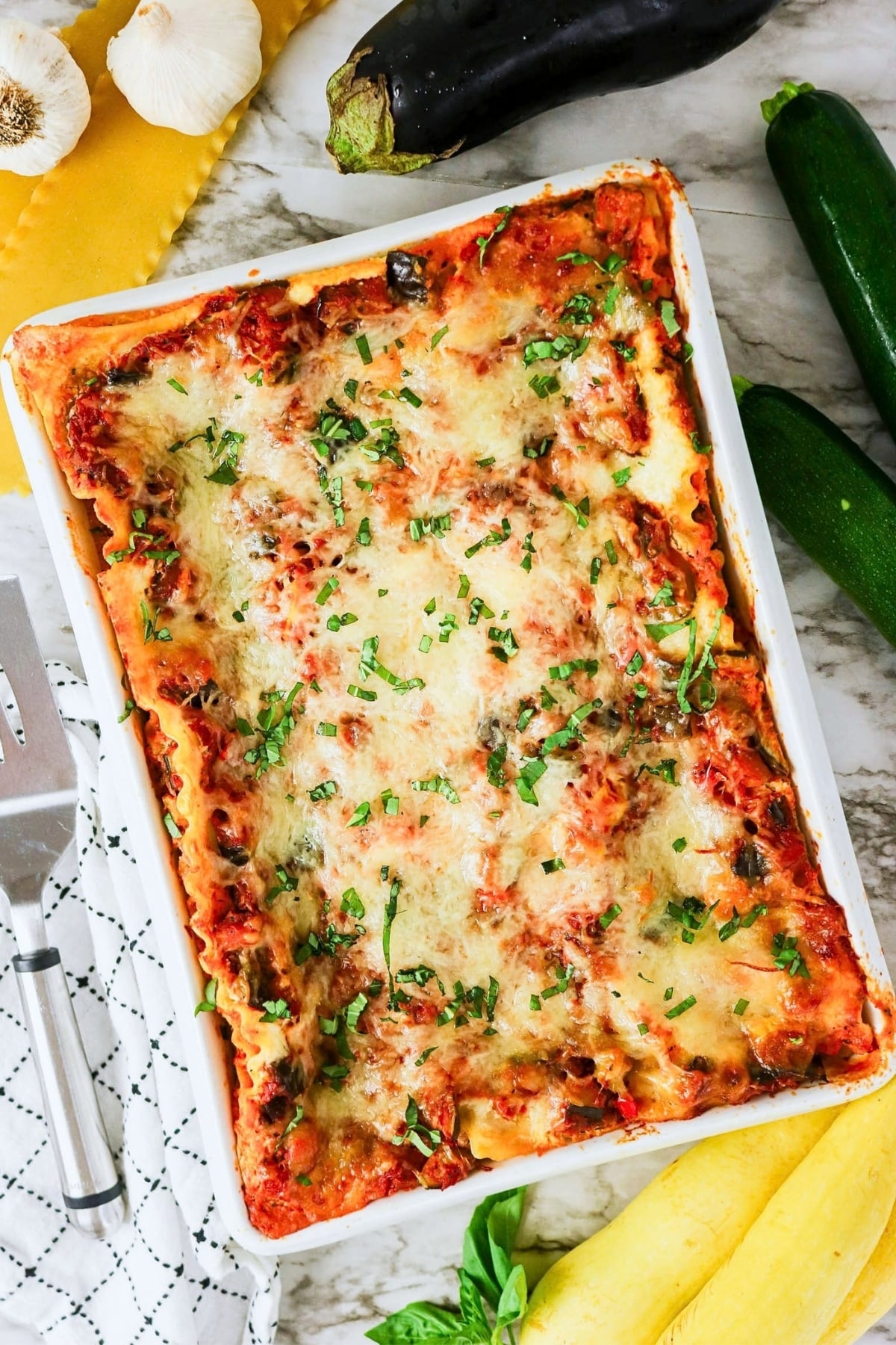 This vegetable lasagna is topped with melted cheese and fresh green herbs.