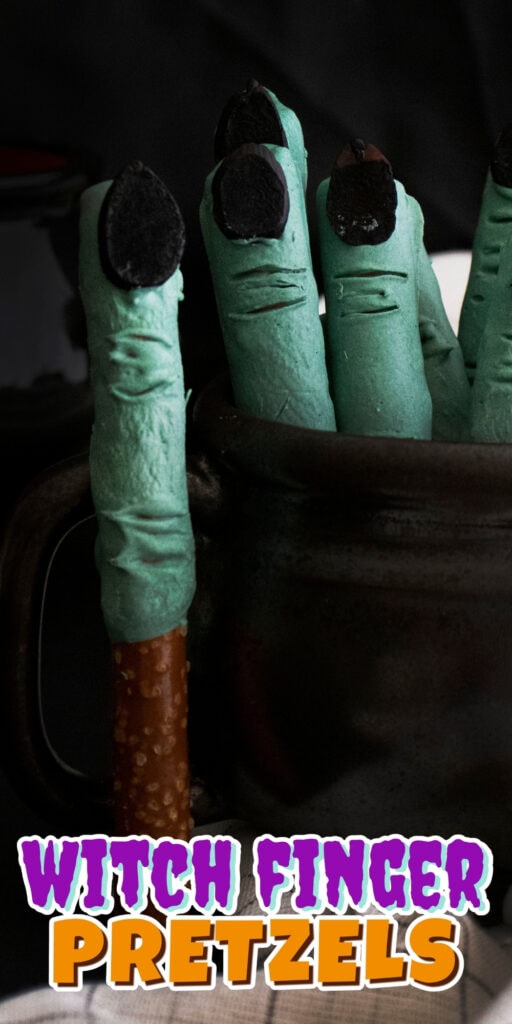 Green witch finger pretzels with black nails in a dark mug.