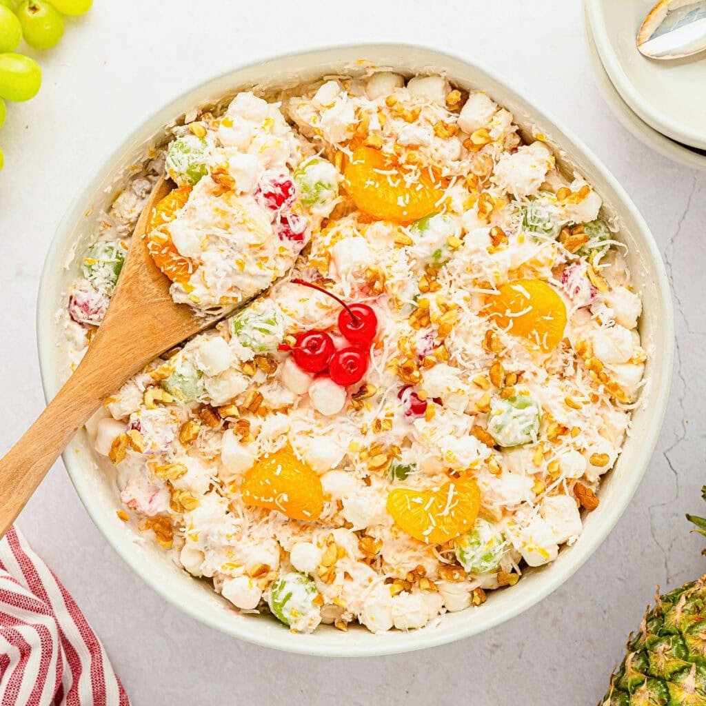 Bowl of fruit salad with marshmallows, mandarin oranges, and cherries.