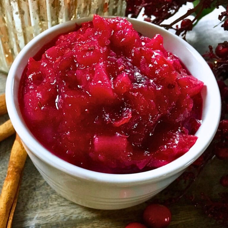 Bowl of chunky cranberry sauce with cinnamon sticks nearby.