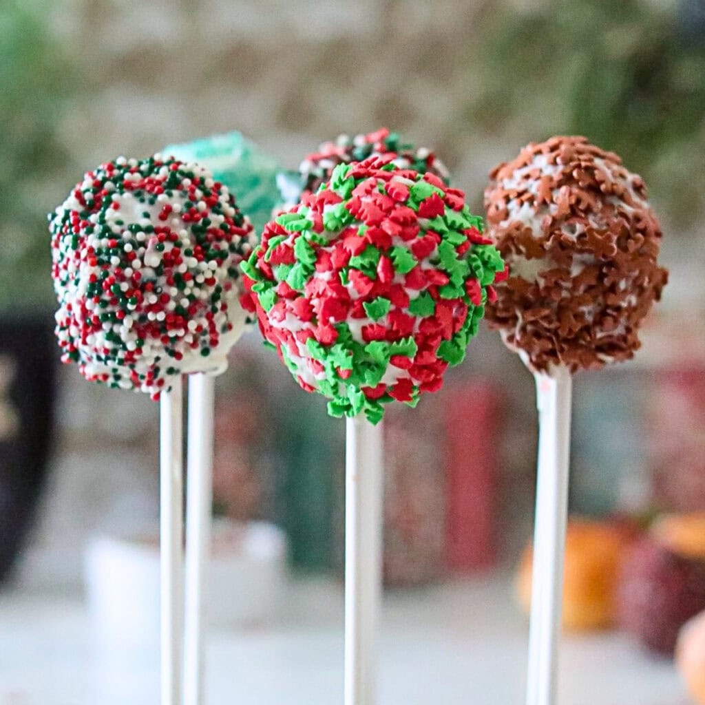 Three cake pops decorated with red, green, and white holiday sprinkles.