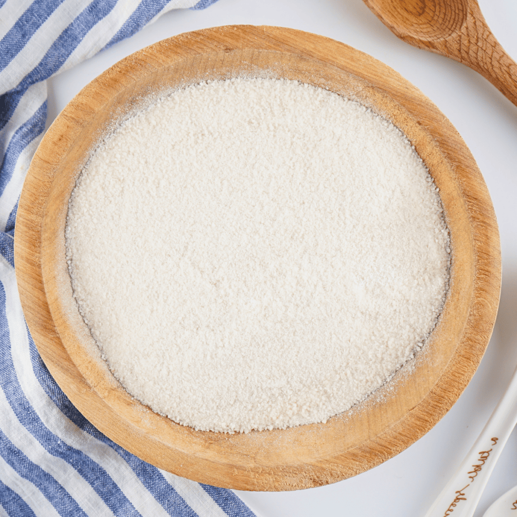 A wooden bowl filled with white flour.