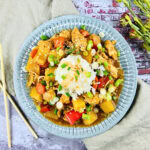 A bowl of stir-fry with rice, chicken, veggies, and sesame seeds.