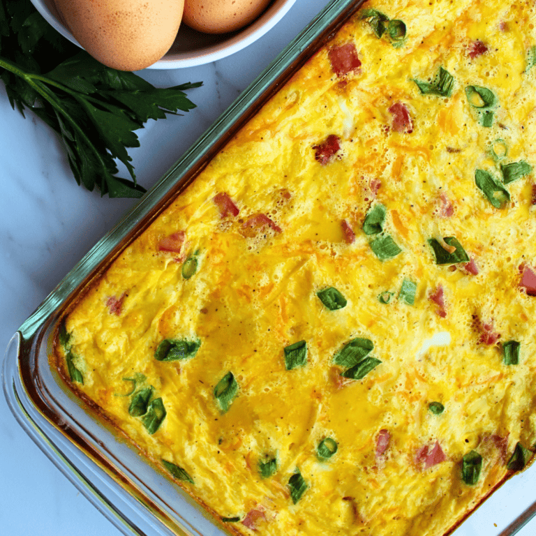 Egg casserole with ham and green onions in a glass baking dish.