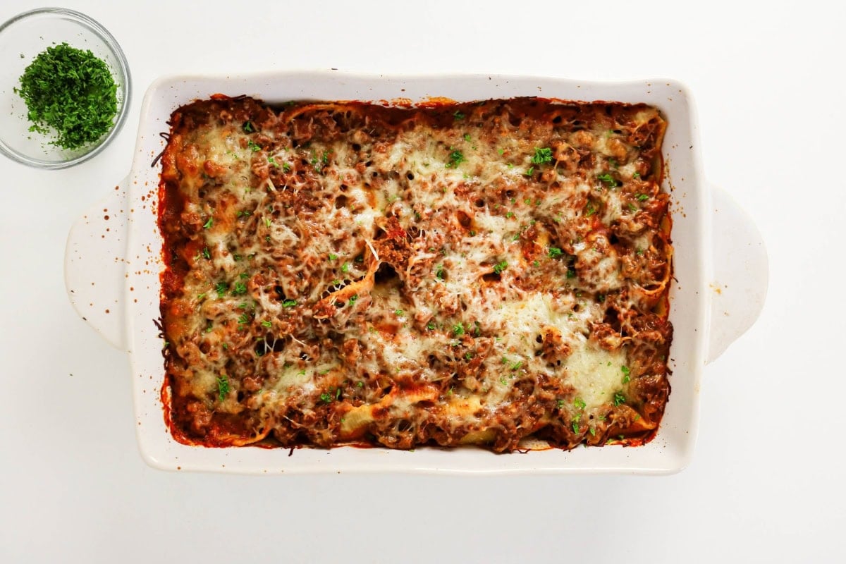 Baked pasta shells with meat sauce and melted cheese in a ceramic dish.