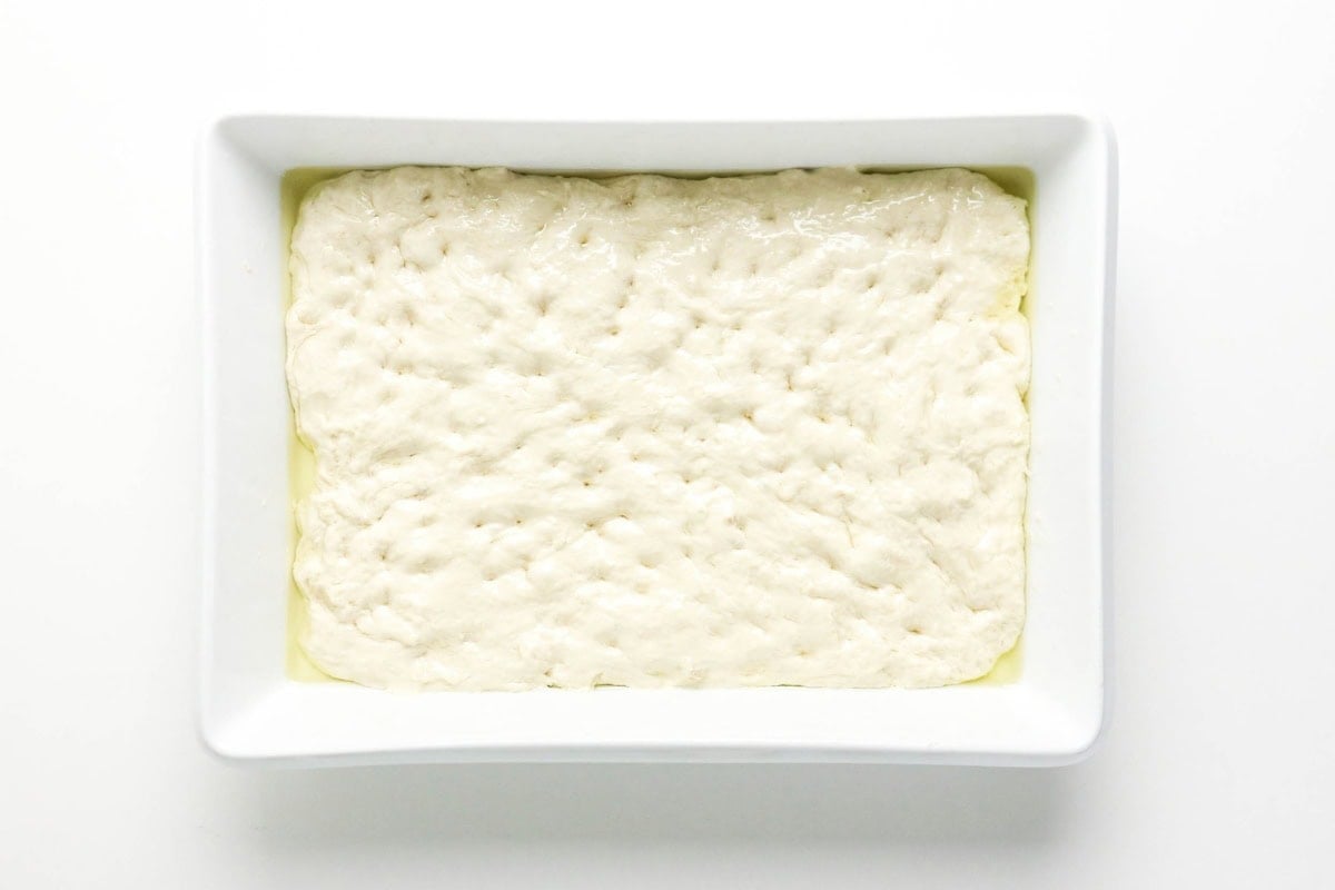 The dough is spread evenly in a rectangular white dish, ready to be baked.