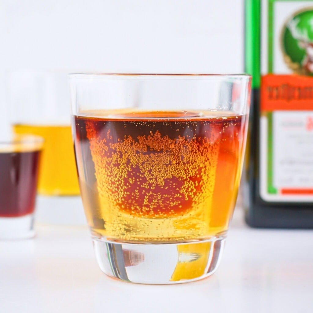 A glass of amber liquor with a small shot glass submerged inside.