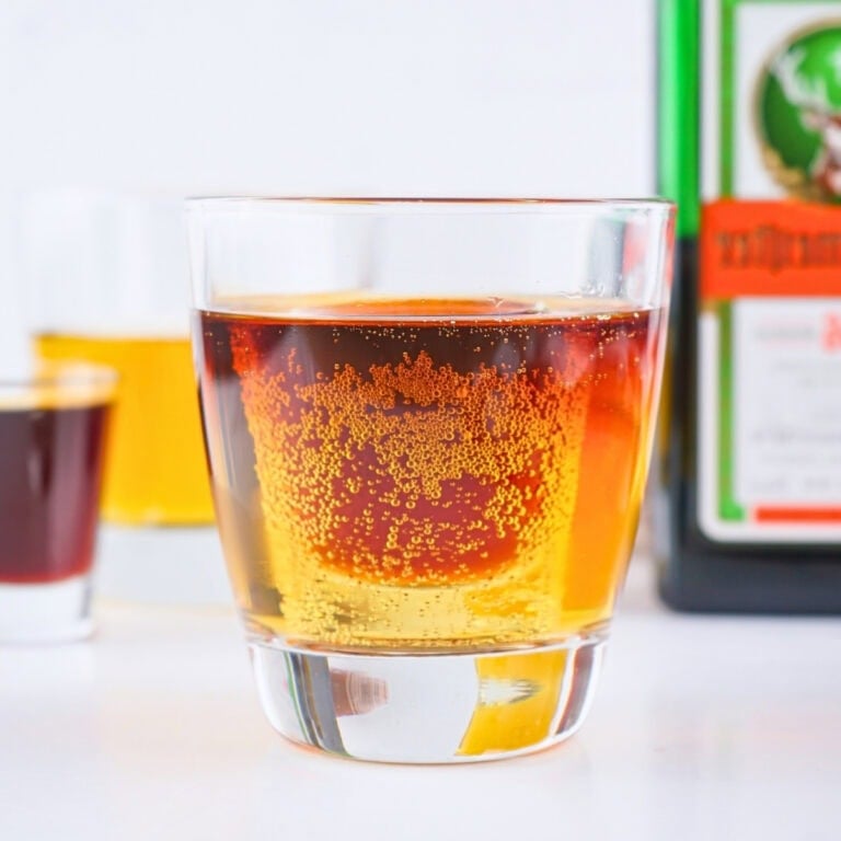 A glass of amber liquor with a small shot glass submerged inside.