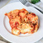 A serving of cheesy pull-apart pizza bread on a white plate with a fork.