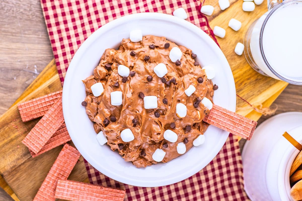 Bowl of chocolate dip with marshmallows and chocolate chips, with wafer cookies.