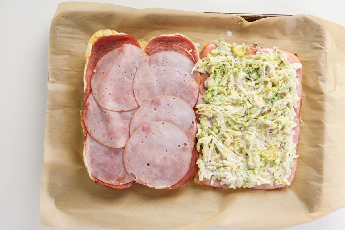 Open sandwich with ham on one side, coleslaw on the other, on parchment paper.