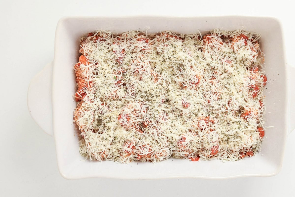 Casserole topped with tomato sauce, shredded cheese, and herbs.