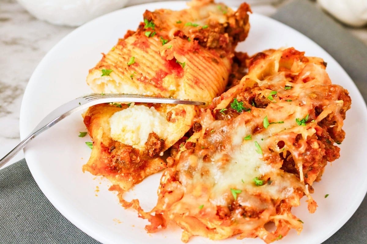 Stuffed jumbo pasta shells with meat sauce and melted cheese on a plate.