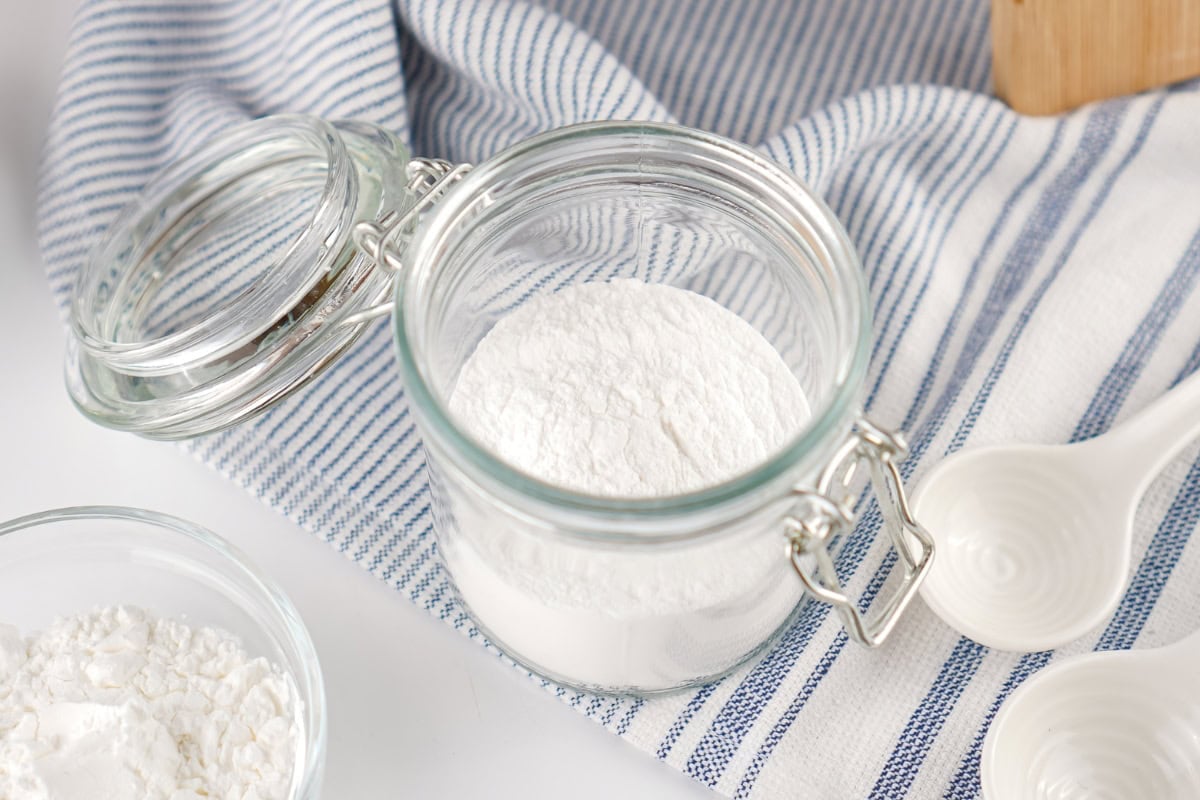 Open glass jar filled with white powder on a striped cloth.