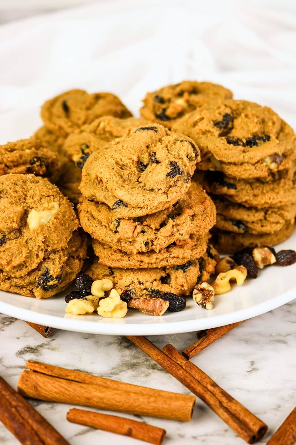 A stack of oatmeal raisin cookies with walnuts on a white plate.