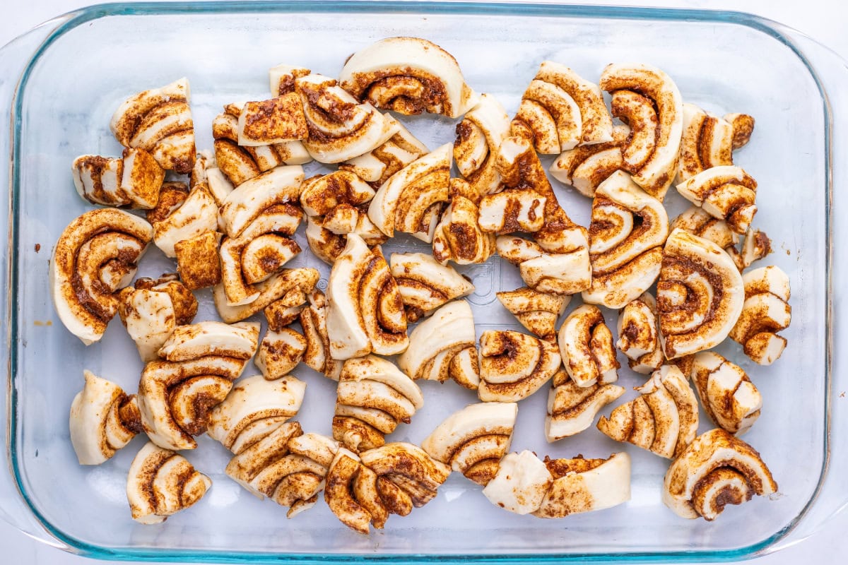 Cinnamon roll pieces arranged in a glass baking dish.