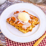 A slice of bread pudding topped with vanilla ice cream and icing.