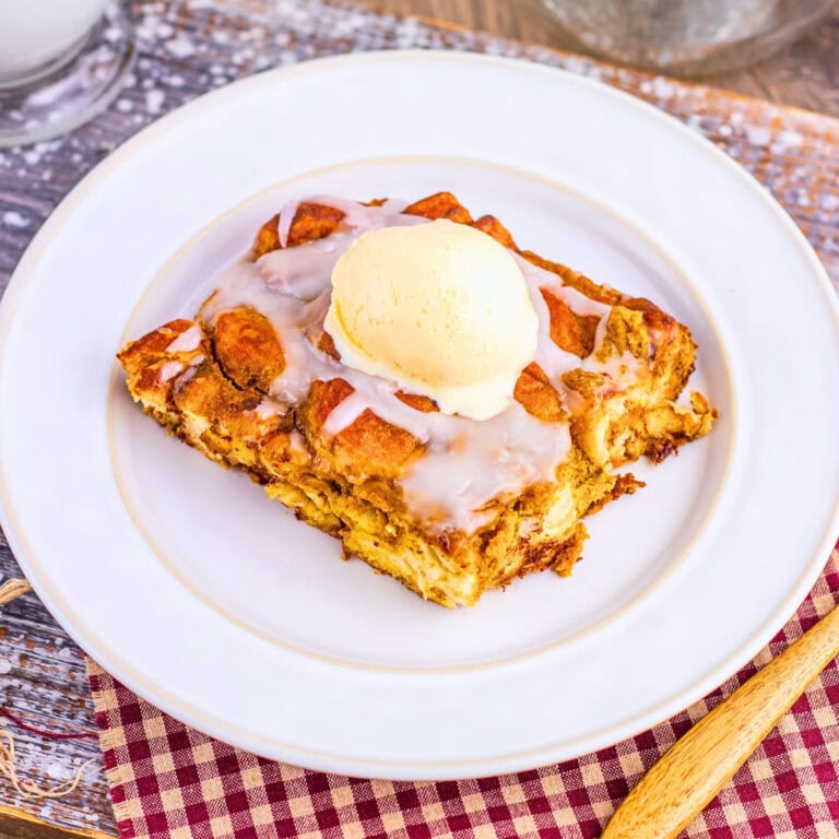 A slice of bread pudding topped with vanilla ice cream and icing.