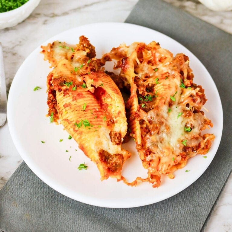 Two baked stuffed pasta shells with meat sauce and melted cheese.